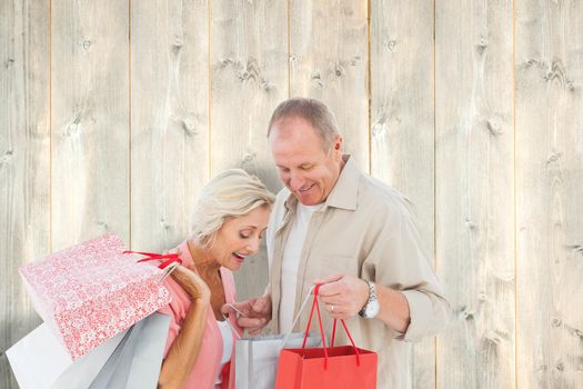 Couple with shopping bags against pale wooden planks