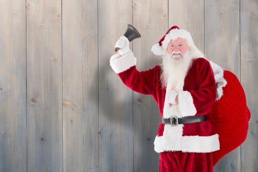 Santa claus ringing bell against pale grey wooden planks