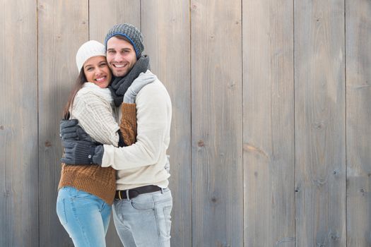 Young winter couple against pale grey wooden planks