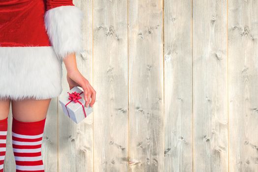 Pretty girl in santa outfit holding gift against pale wooden planks