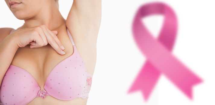 Woman performing self breast examination against breast cancer awareness ribbon