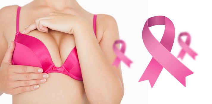 Closeup of woman performing self breast examination against pink breast cancer awareness ribbons