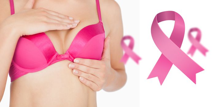 Woman performing self breast examination against pink breast cancer awareness ribbons