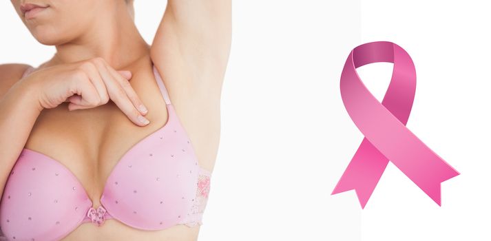 Woman performing self breast examination against breast cancer awareness ribbon