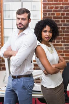 Portrait of two confident young business people with arms crossed in office