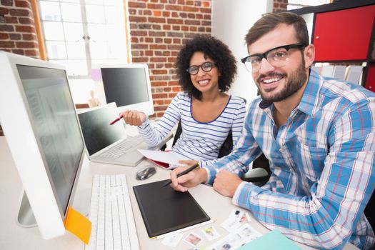 Portrait of smiling photo editors using digitizer in the office