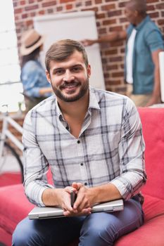 Portrait of young casual man sitting on couch in the office