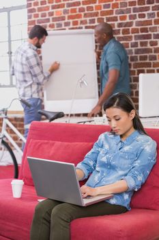 Young casual woman using laptop on couch in the office