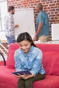 Young casual woman using digital tablet on couch in the office