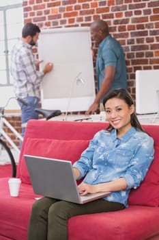 Young casual woman using laptop on couch in the office