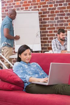 Young casual woman using laptop on couch in the office