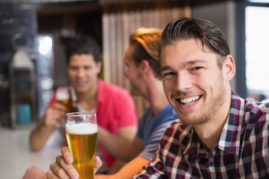 Young man holding pint of beer at the bar