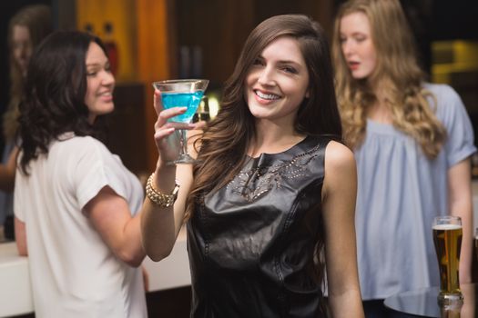 Pretty brunette holding a cocktail at the bar