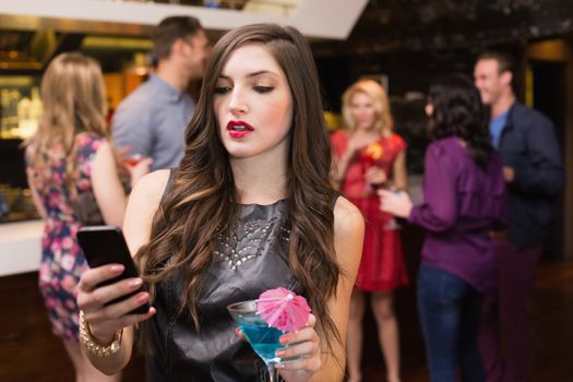 Pretty brunette sending a text at the bar