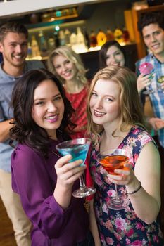 Pretty friends drinking cocktails together at the bar