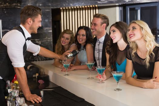 Attractive friends drinking cocktails together at the bar