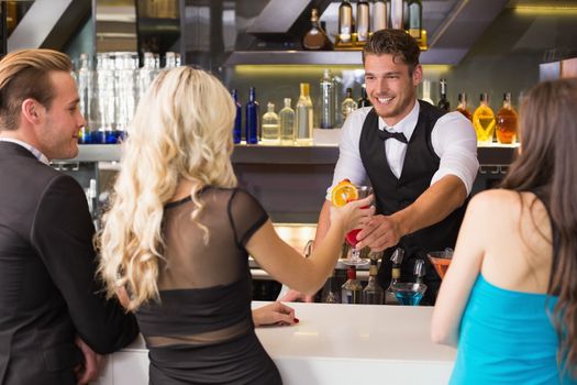 Attractive friends being served cocktails at the bar