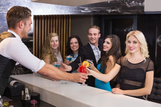 Attractive friends being served cocktails at the bar