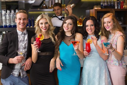 Attractive friends drinking cocktails together at the bar