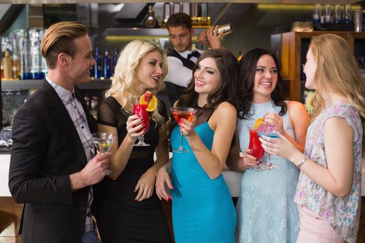 Attractive friends drinking cocktails together at the bar