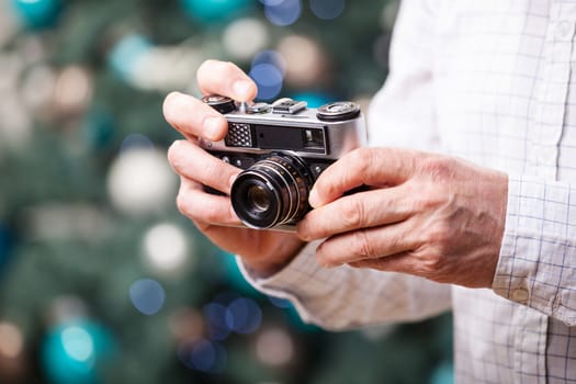 Cropped view of man holding retro camera against Christmas background