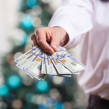 Male hand with money on a Christmas background