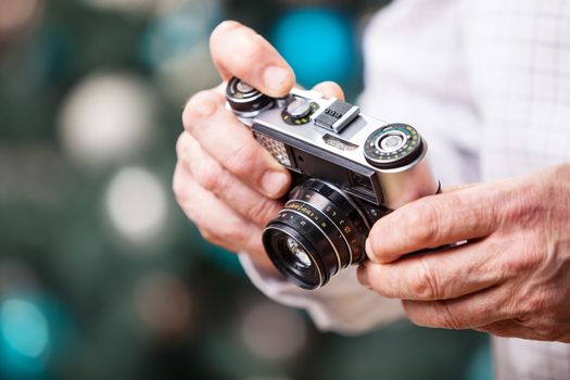 Cropped view of man holding retro camera against Christmas background