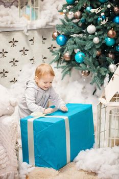 Toddler boy opening a box with gift on Christmas background
