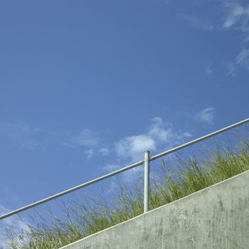 Industrial hand rail with grass and blue sky