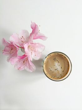 Lavender latte next to a bouquet of pink flowers