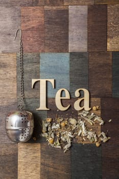 Tea time words, Tea Infuser and dry mountain tea leaves on wooden background