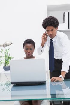 Concentrated colleagues using laptop and phoning in the office