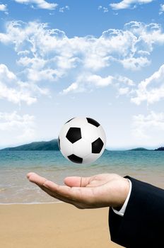 Beach football in businessman hand