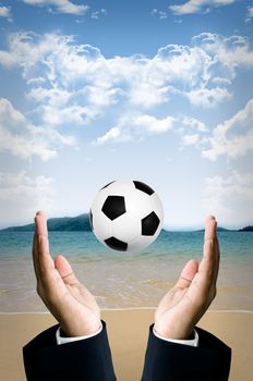 Beach football in businessman hand