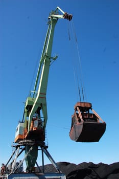 Crane loading coal to ship at Kolyma river port, Russia