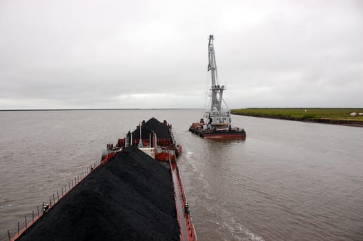 Ship with coal and crane at Kolyma river, Russia
