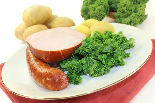 a white plate with kale, smoked meat and pee sausage