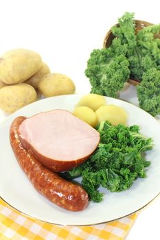 a white plate with kale, smoked meat and pee sausage