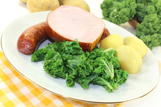 a white plate with kale, smoked meat and pee sausage