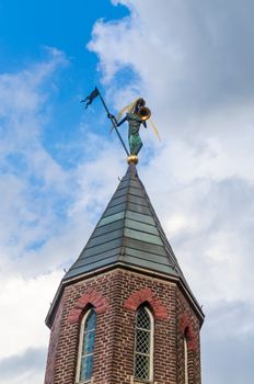 Church spire with trombonist before blue sky