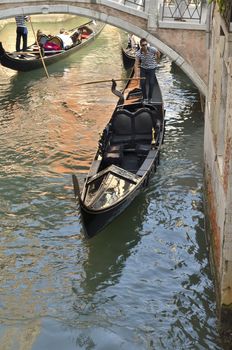 Gondolier passing under a bridge in Venice, Italy