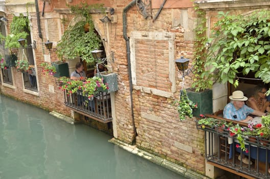 People eating in a restaurant with views to the canal in in Venice, Italy