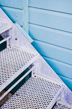 Metal stairs againts a blue wooden wall