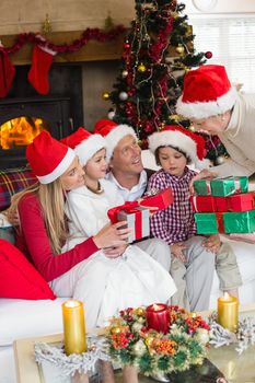 Family wearing christmas hat while holding presents at home in the living room