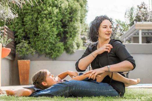 Mother and daughter playing outside in the back garden on a nice summer day, spending quality time with each other.