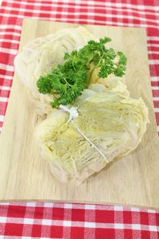 two stuffed savoy cabbage leaves and parsley on a wooden board