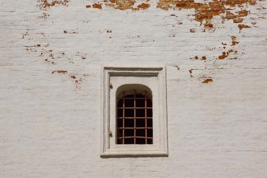 window with iron bars on white brick wall