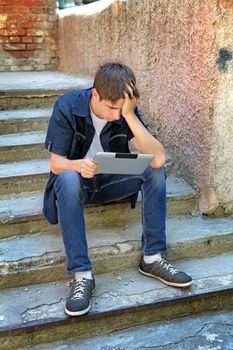 Sad Teenager with Tablet Computer on the landing steps of the House