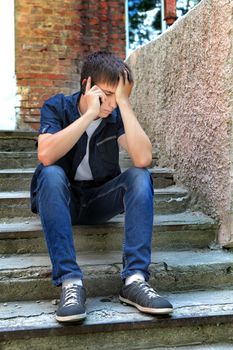 Sad Teenager with Cellphone on the landing steps of the Old House