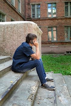 Teenager with Cellphone on the landing steps of the House